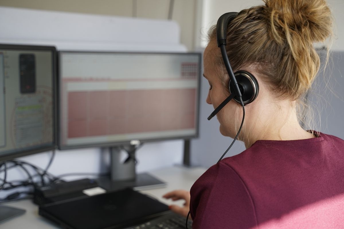 Kvinde i vagtcentral besvarer opkald foran computerskærm
